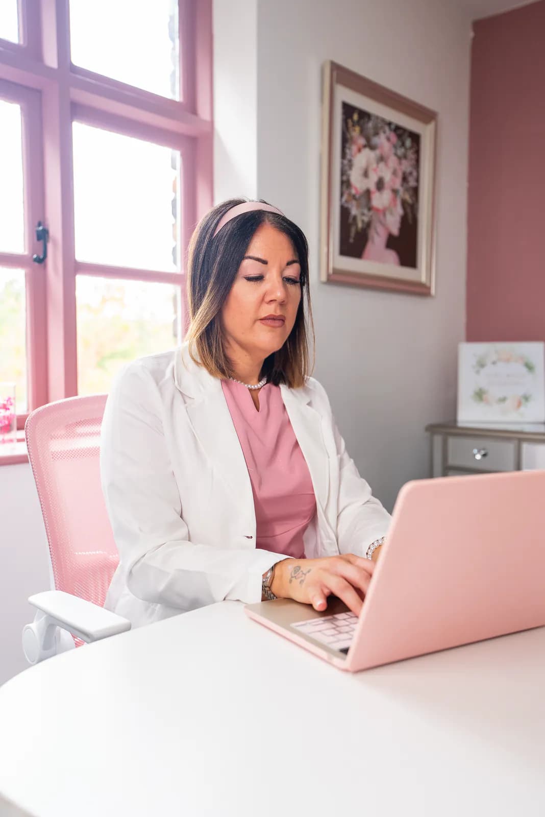 A member of the academy team working through course details at a pink laptop in Cherry Tree House.